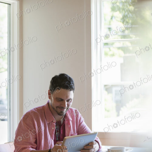 A man sitting at a cafe table, using a digital tablet. A man sitting at a cafe table, using a digital tablet.