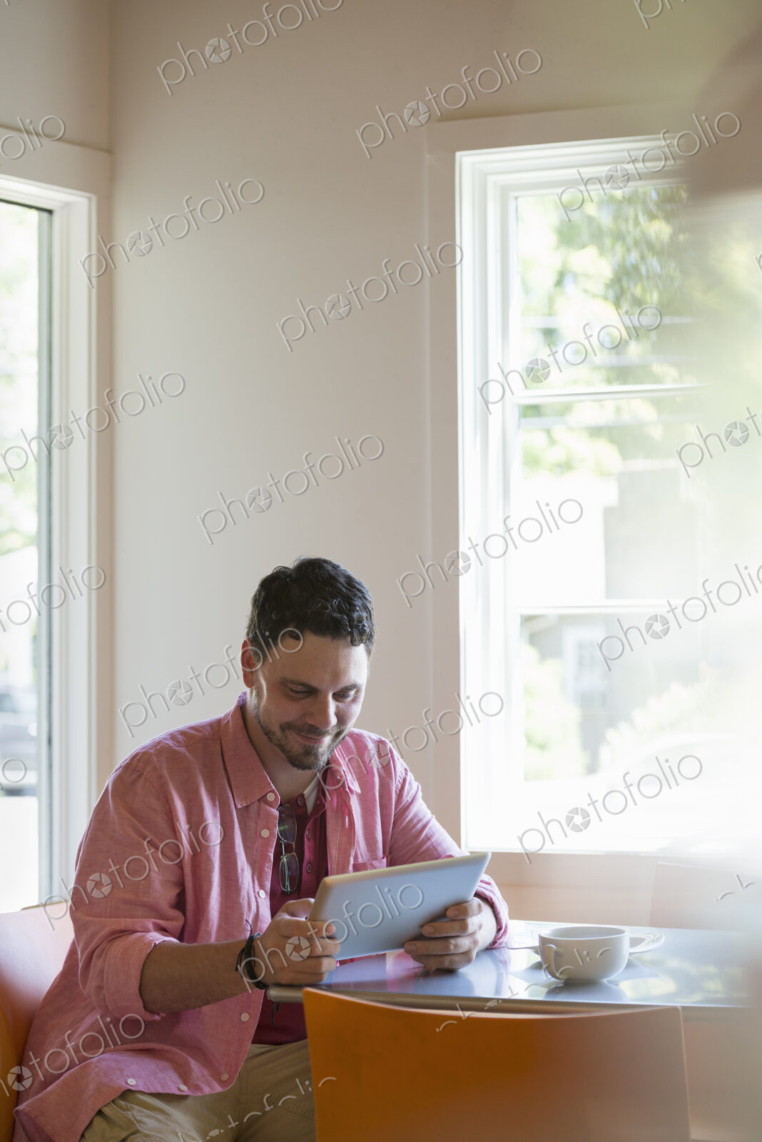 A man sitting at a cafe table, using a digital tablet.