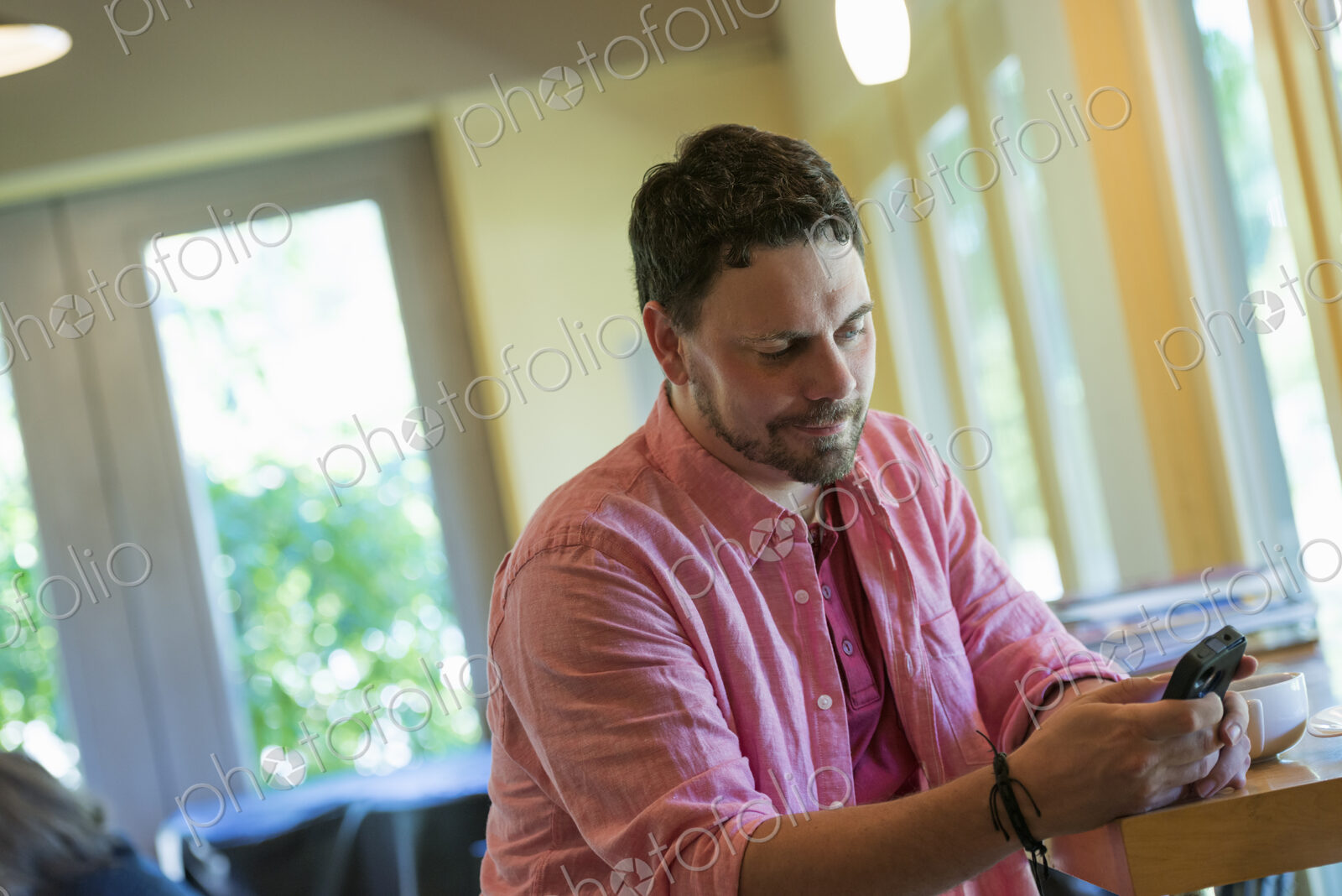 A man sitting at a cafe table, using a smart phone.