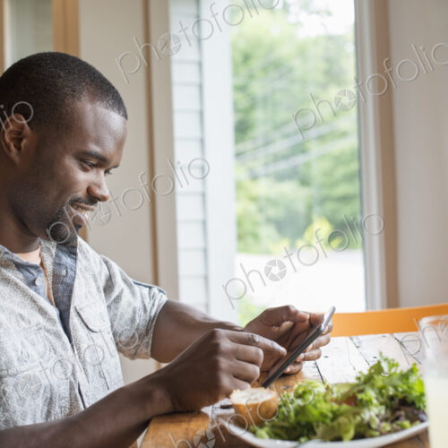 A man sitting in a cafe with a cup of coffee, using a smart phone. A man sitting in a cafe with a cup of coffee, using a smart phone.