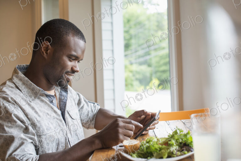 A man sitting in a cafe with a cup of coffee, using a smart phone.