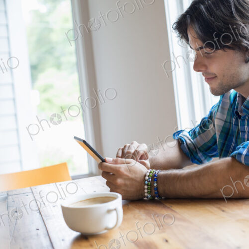 A man sitting in a cafe with a cup of coffee. Using a digital tablet. A man sitting in a cafe with a cup of coffee. Using a digital tablet.