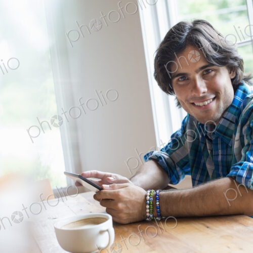 A man sitting in a cafe with a cup of coffee. Using a digital tablet. A man sitting in a cafe with a cup of coffee. Using a digital tablet.