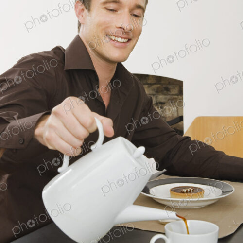 A man sitting pouring a cup of coffee, having breakfast. A man sitting pouring a cup of coffee, having breakfast.