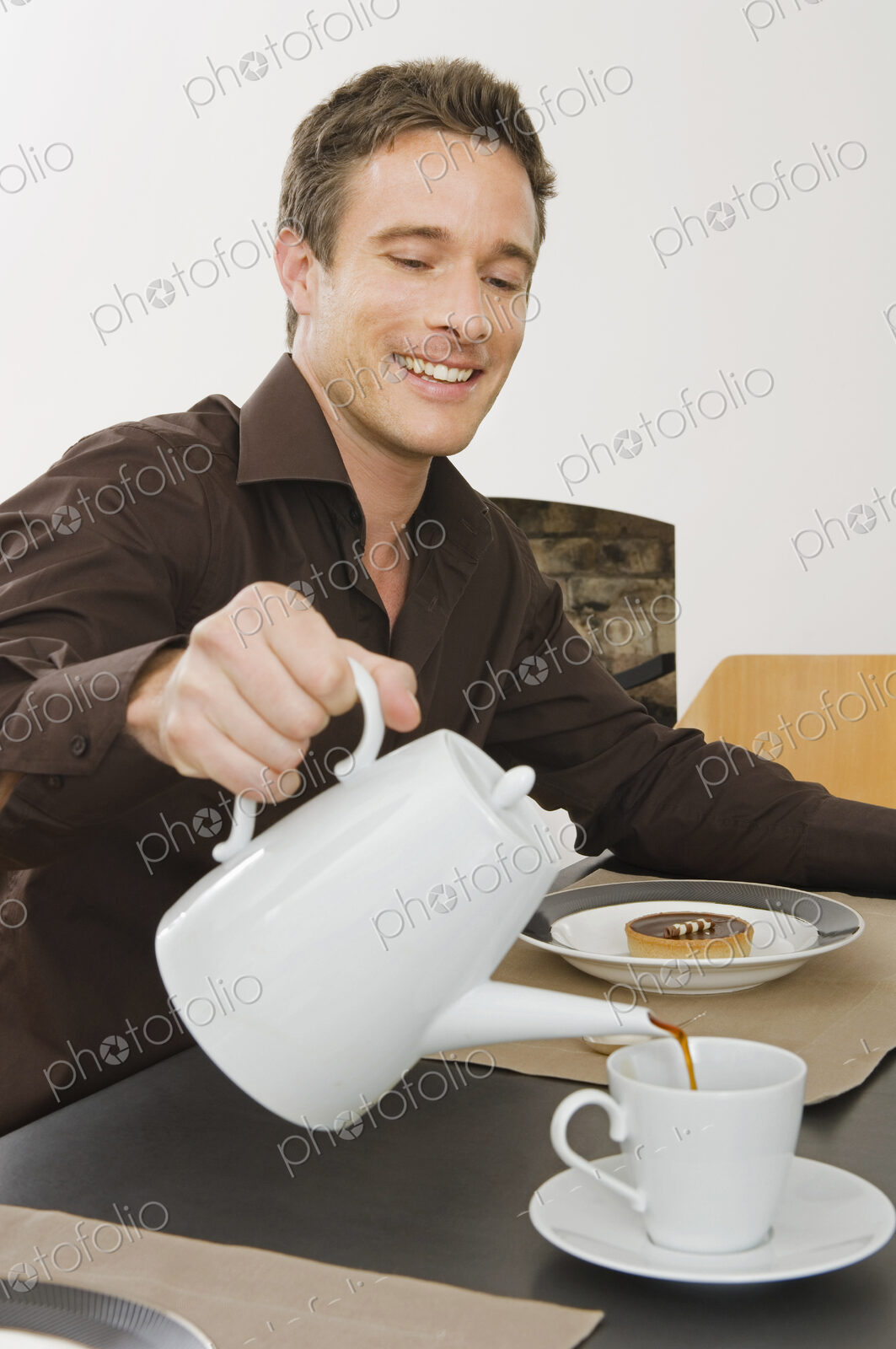 A man sitting pouring a cup of coffee, having breakfast.