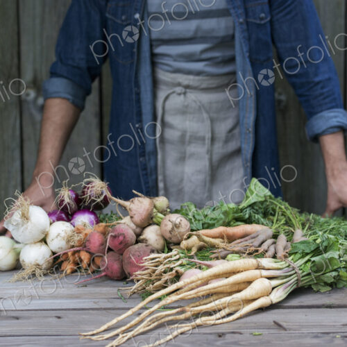 A man sorting freshly picked vegetables on a table. A man sorting freshly picked vegetables on a table.