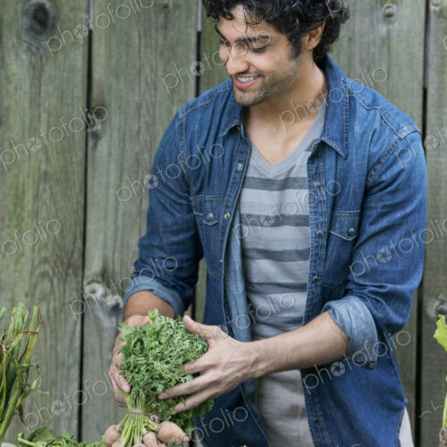 A man sorting freshly picked vegetables on a table. A man sorting freshly picked vegetables on a table.