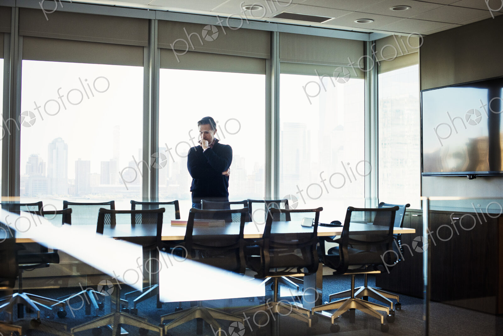 A man standing at a table in a meeting room looking down at an open book.