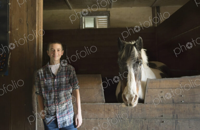 A man standing beside a horsebox in the stables at an animal sanctuary. A horse with…