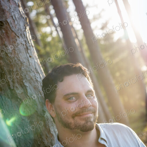 A man standing in woodland by a lake. A man standing in woodland by a lake.