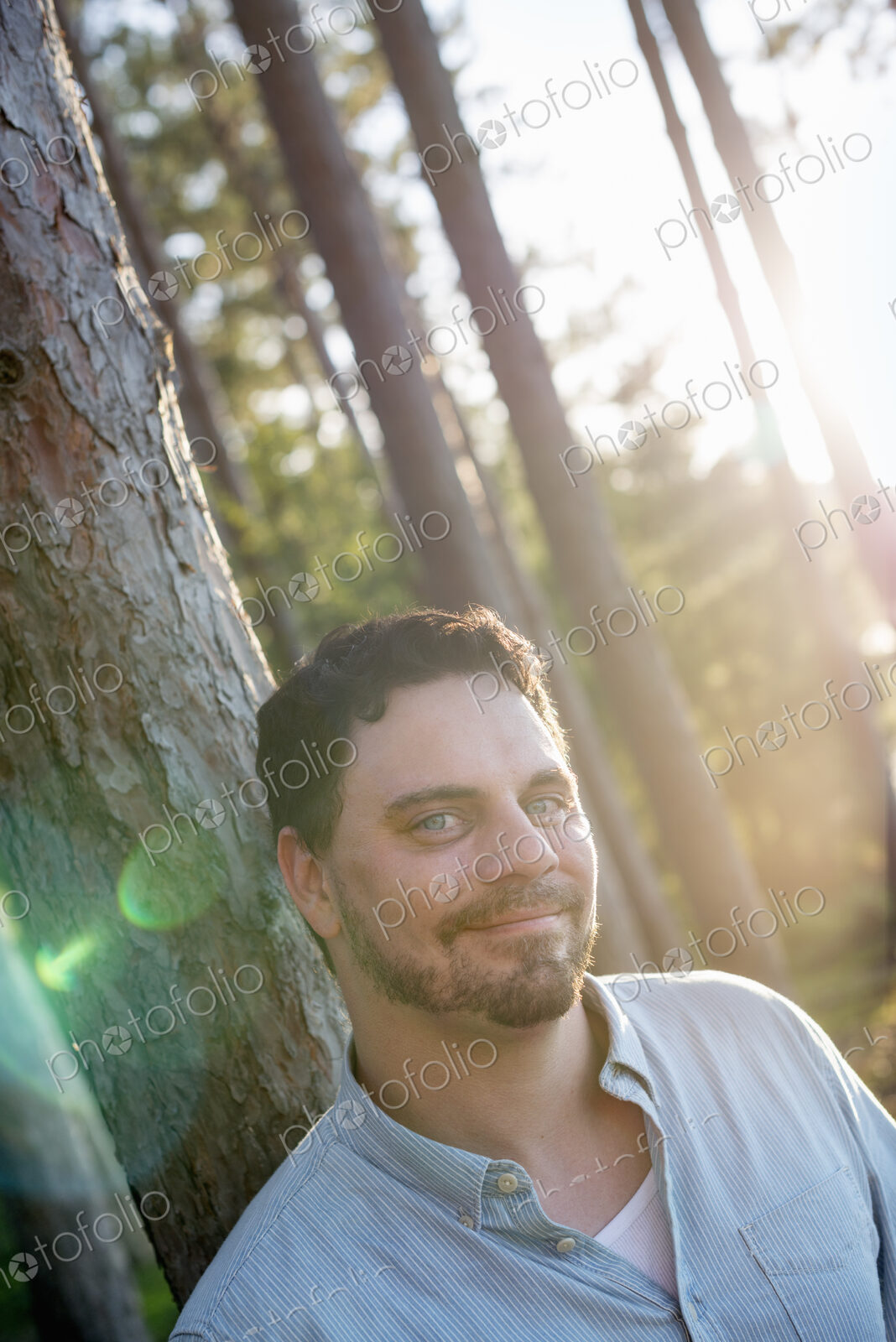 A man standing in woodland by a lake.