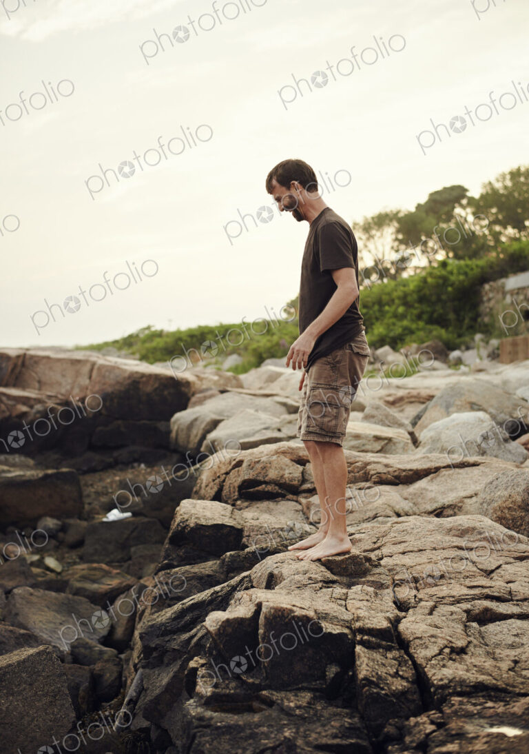 A man standing on the beach, overlooking the rockpools.