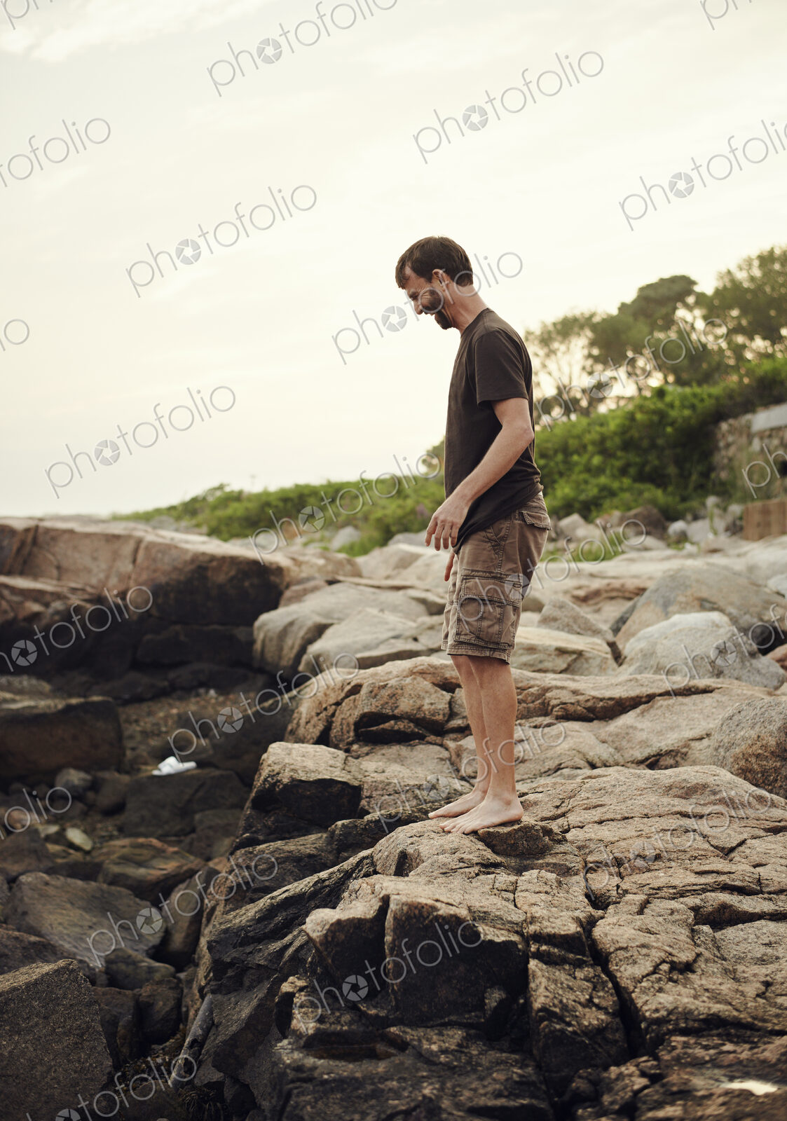 A man standing on the beach, overlooking the rockpools.