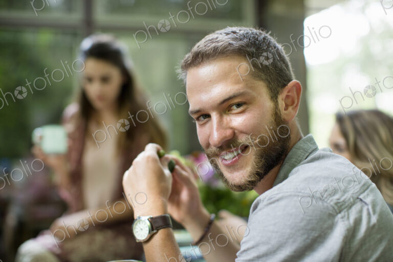 A man turning is head, seated at a table with a group of people.