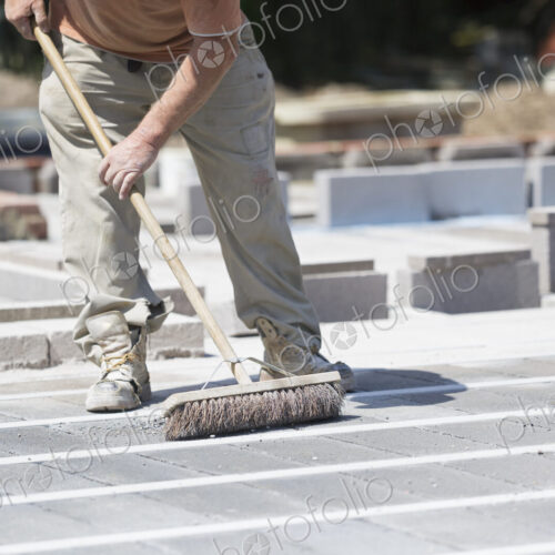 A man using a brush on a cement floor on a construction site.