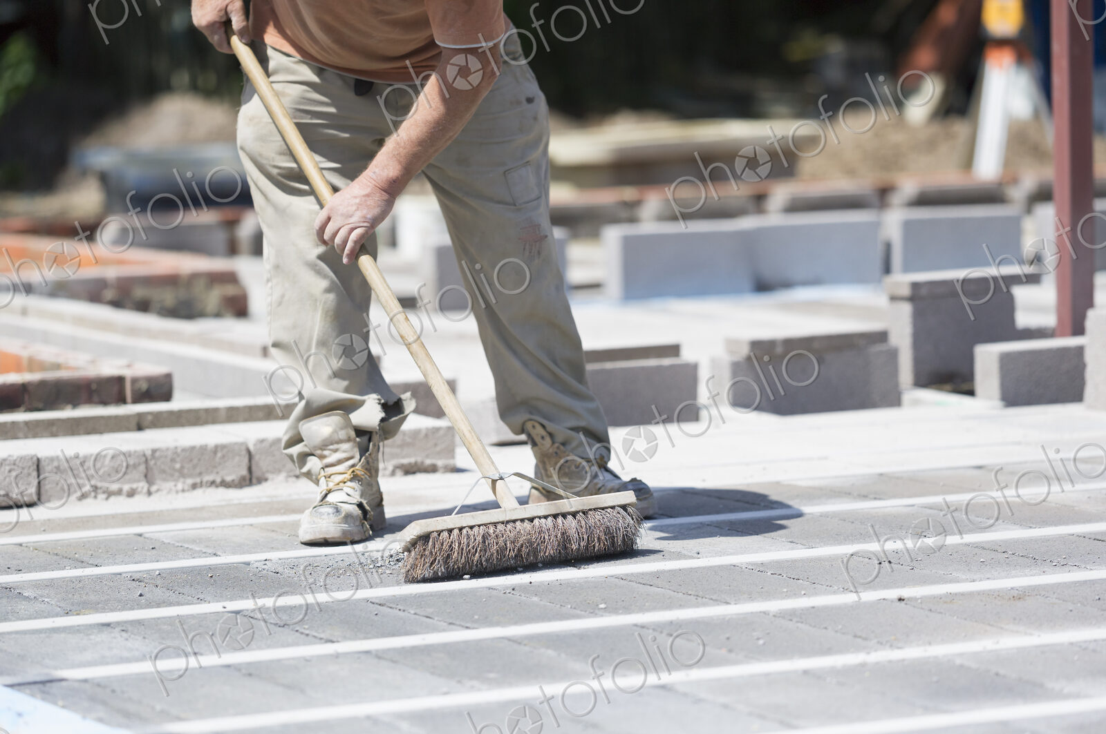 A man using a brush on a cement floor on a construction site.