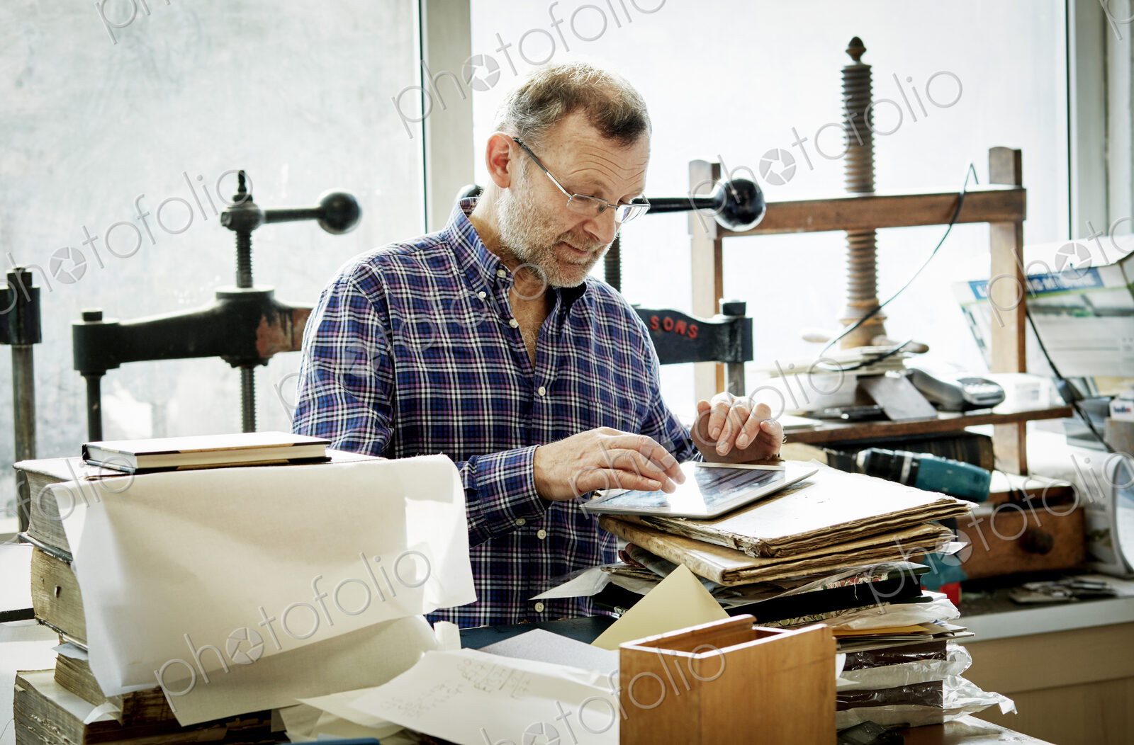A man using a digital tablet in a bookbinding workshop.