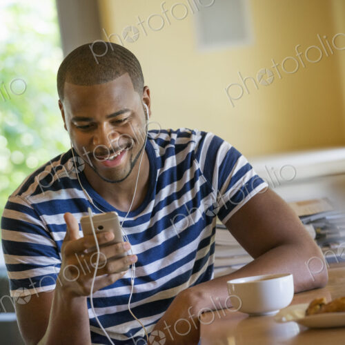 A man using a smart phone, or personal music player, wearing headphones.