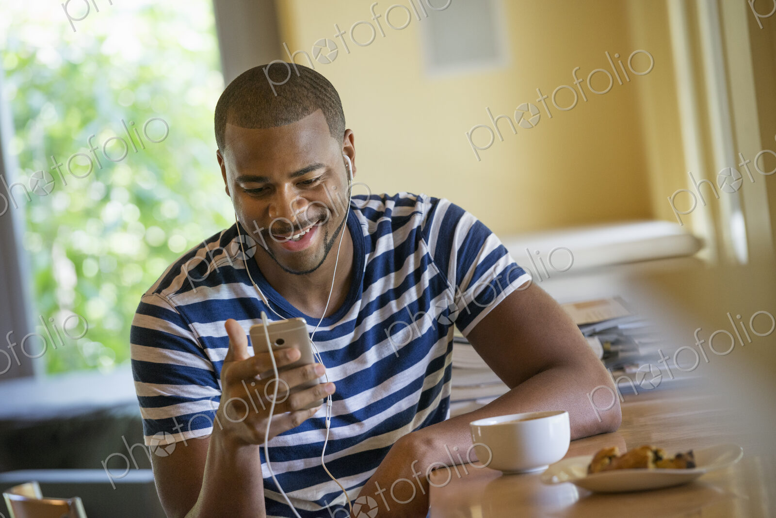 A man using a smart phone, or personal music player, wearing headphones.