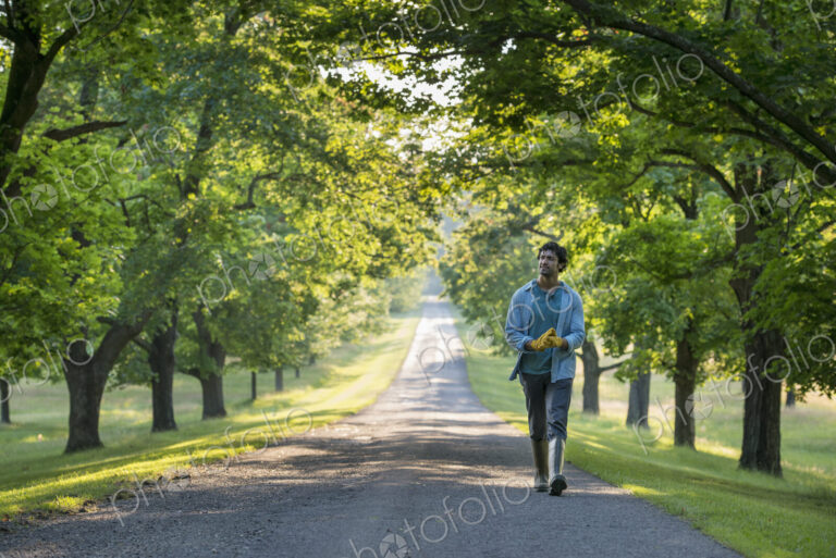A man walking down a tree lined path.
