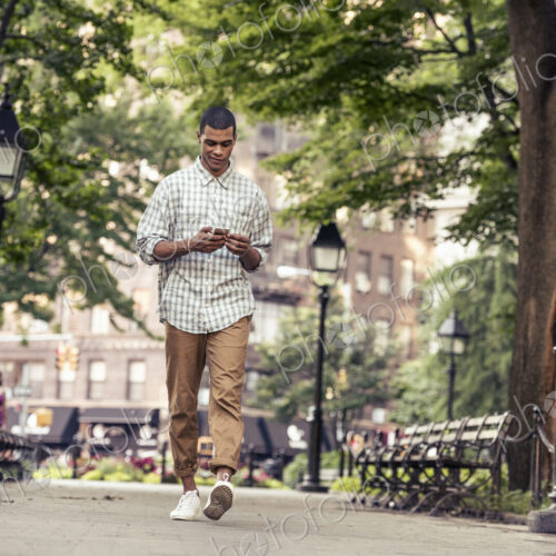 A man walking through a town square looking at his smart phone A man walking through a town square looking at his smart phone