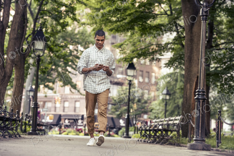 A man walking through a town square looking at his smart phone