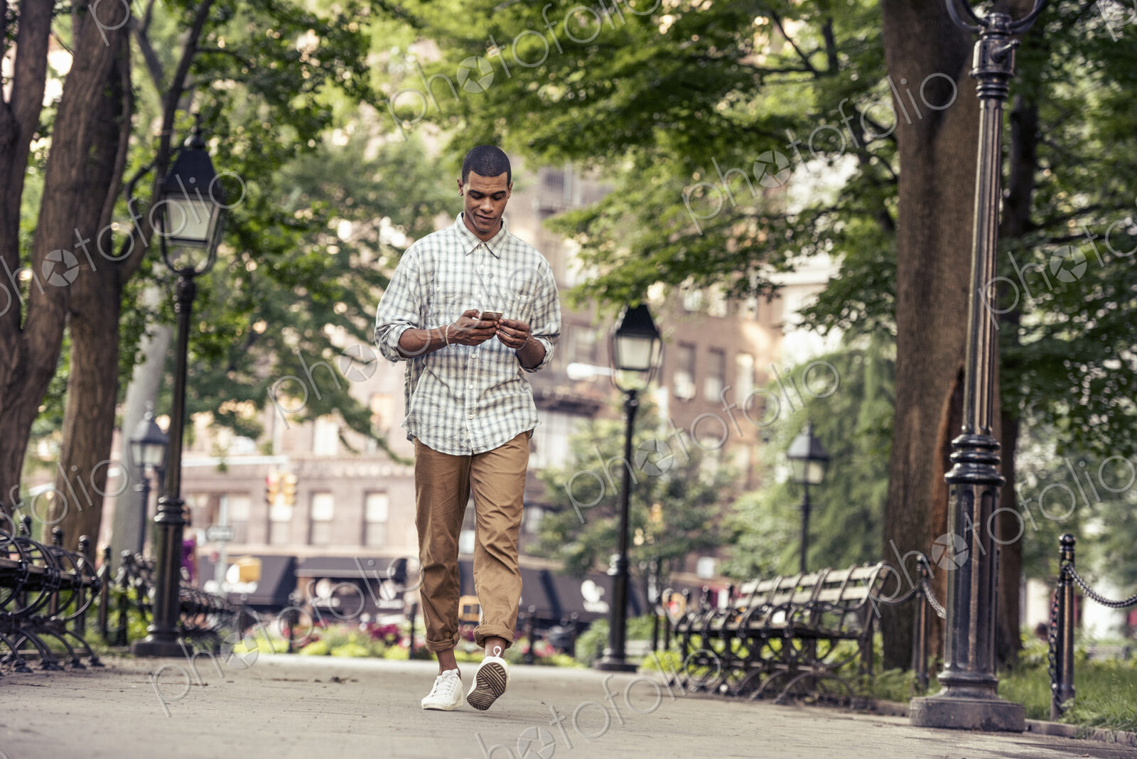 A man walking through a town square looking at his smart phone