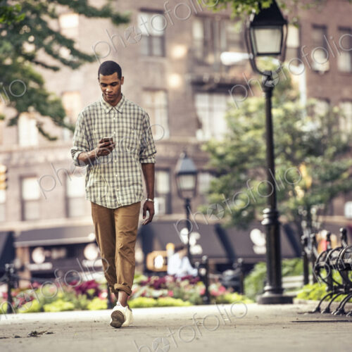 A man walking through a town square looking at his smart phone A man walking through a town square looking at his smart phone
