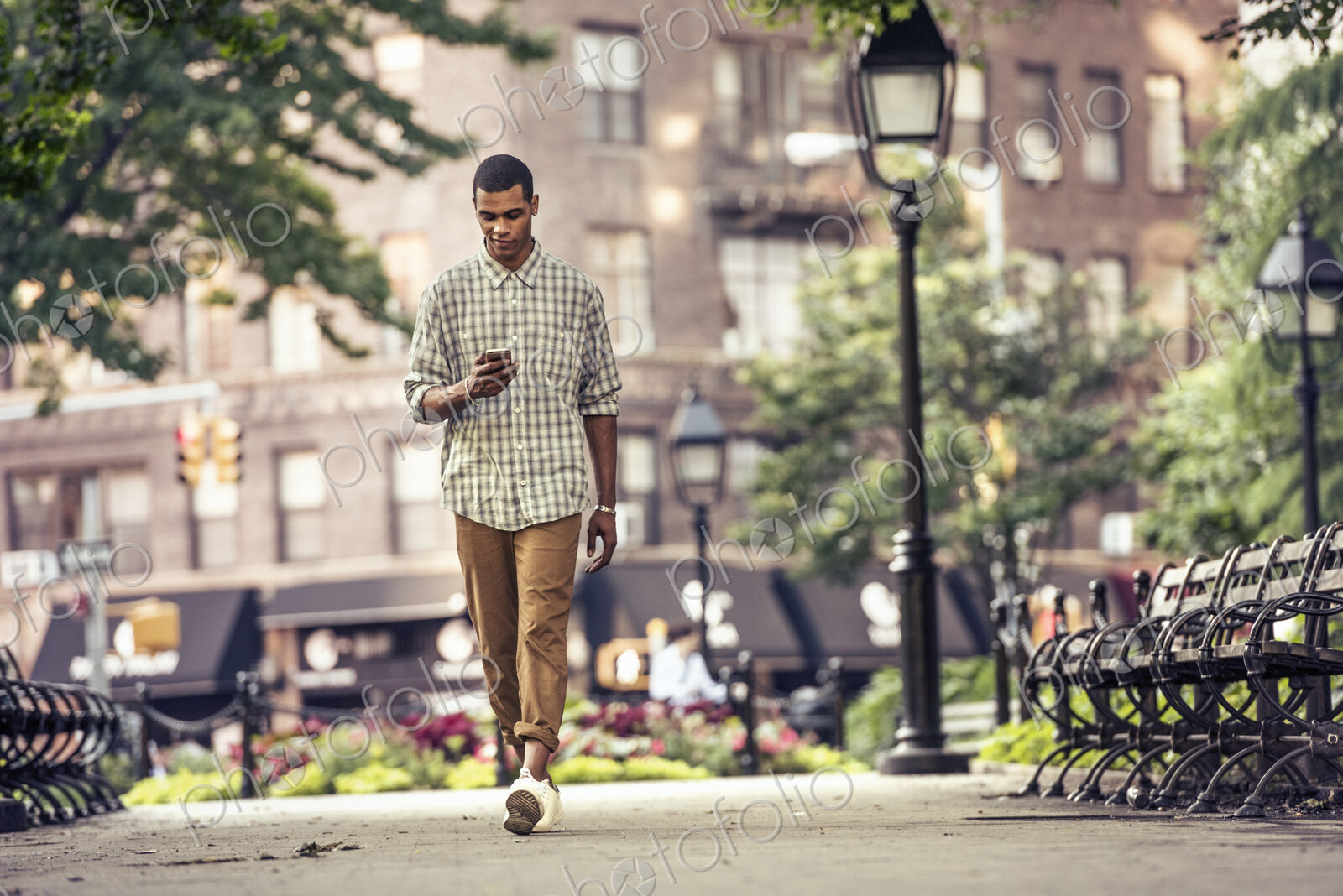 A man walking through a town square looking at his smart phone