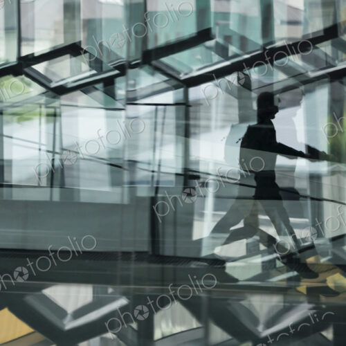 A man walking through the Harpa building, with glass walls and reflected light. A man walking through the Harpa building, with glass walls and reflected light.