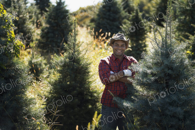 A man wearing a checked shirt and large brimmed hat in a plantation of organic…