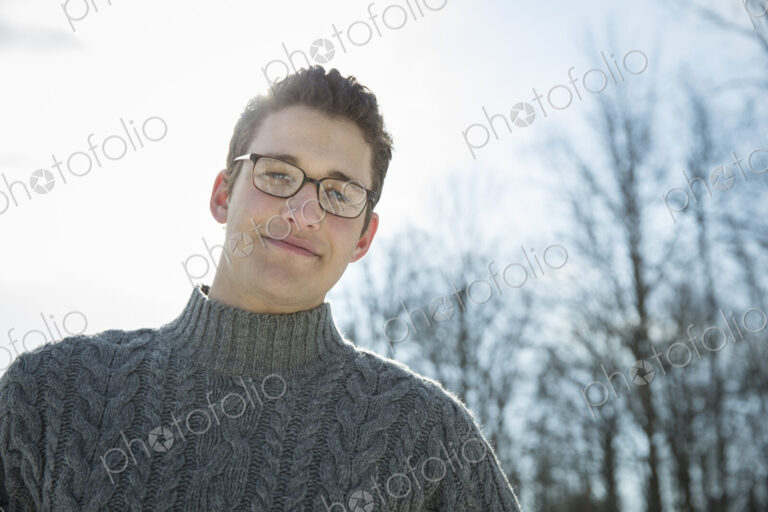 A man wearing a woollen jumper, looking at the camera. A cold winter day.