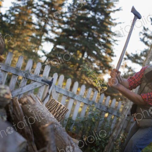 A man wielding an axe, and chopping wood, splitting logs for the fire. A man wielding an axe, and chopping wood, splitting logs for the fire.
