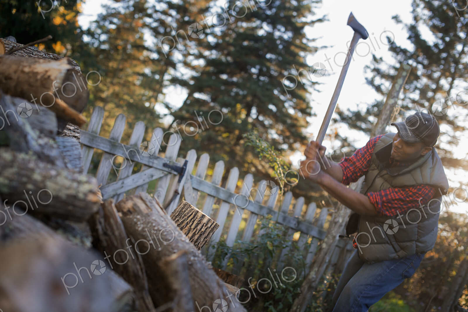 A man wielding an axe, and chopping wood, splitting logs for the fire.