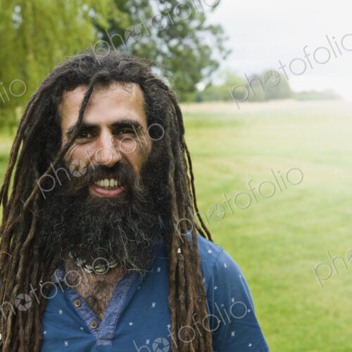 A man with long dreadlocks in a blue shirt.