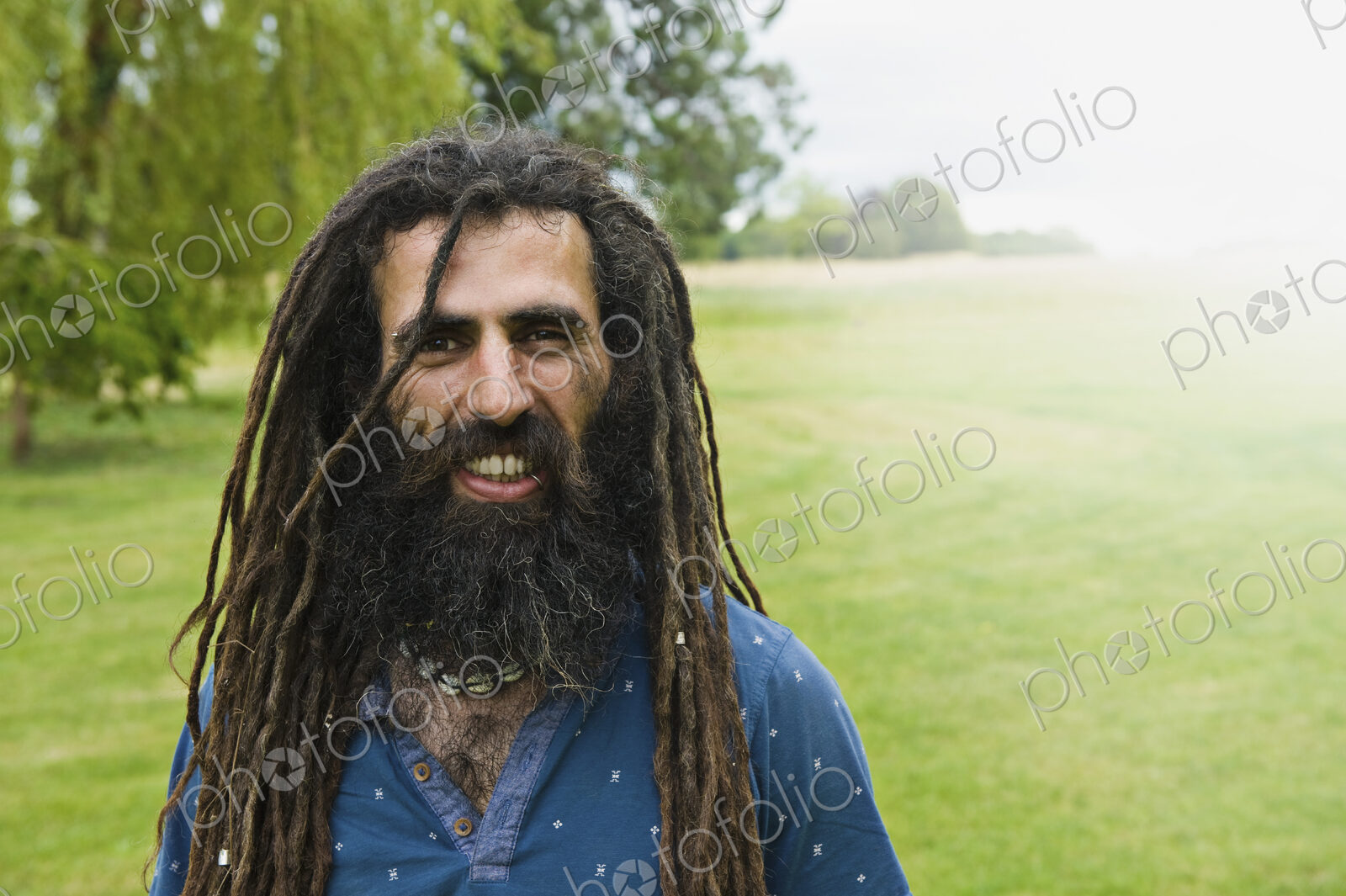 A man with long dreadlocks in a blue shirt.