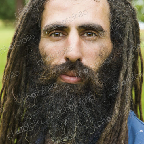 A man with long dreadlocks in a blue shirt.