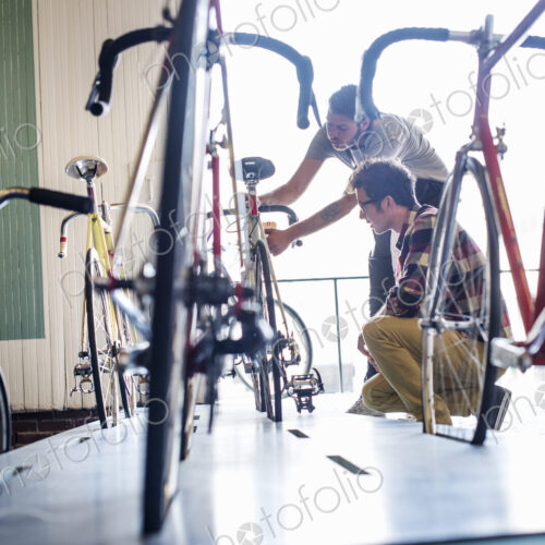 A man working in a bicycle repair shop, checking a bike with a customer. A man working in a bicycle repair shop, checking a bike with a customer.