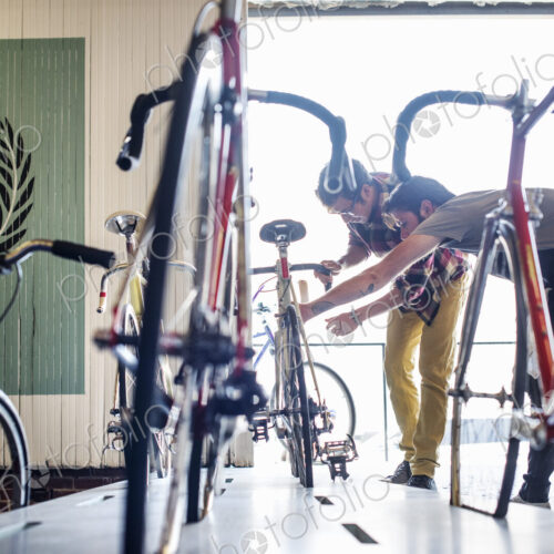 A man working in a bicycle repair shop, checking a bike with a customer. A man working in a bicycle repair shop, checking a bike with a customer.