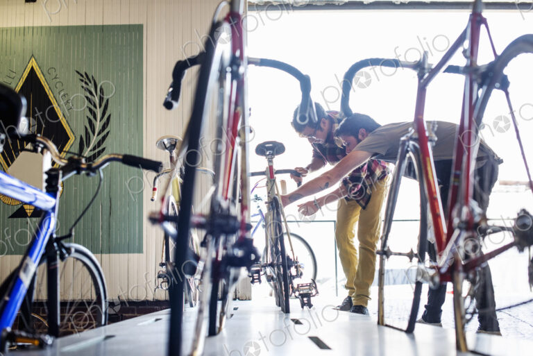 A man working in a bicycle repair shop, checking a bike with a customer.