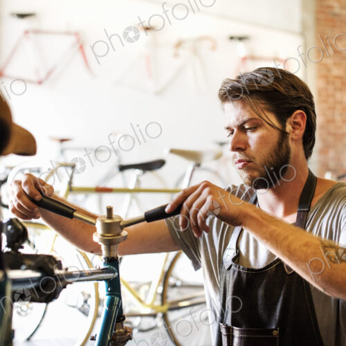 A man working in a bicycle repair shop, checking the frame of the bike. A man working in a bicycle repair shop, checking the frame of the bike.