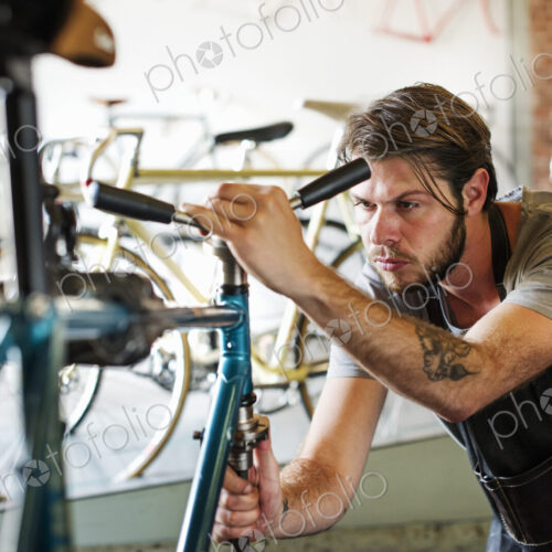 A man working in a bicycle repair shop, checking the frame of the bike. A man working in a bicycle repair shop, checking the frame of the bike.