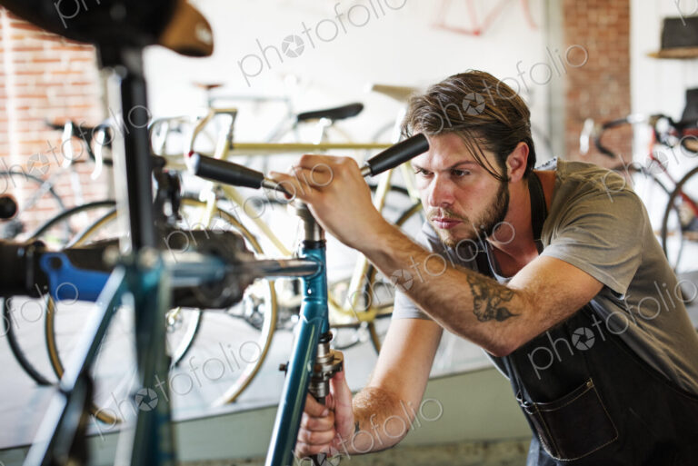 A man working in a bicycle repair shop, checking the frame of the bike.