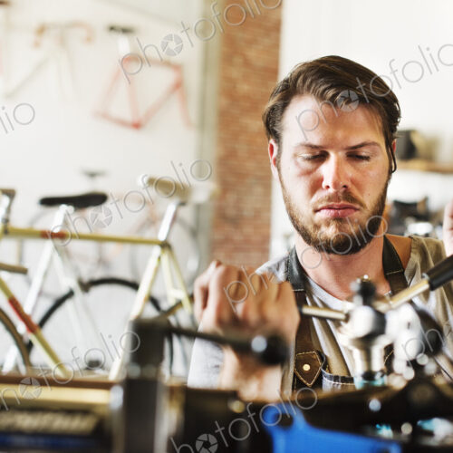 A man working in a bicycle repair shop, checking the frame of the bike. A man working in a bicycle repair shop, checking the frame of the bike.