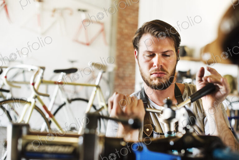 A man working in a bicycle repair shop, checking the frame of the bike.