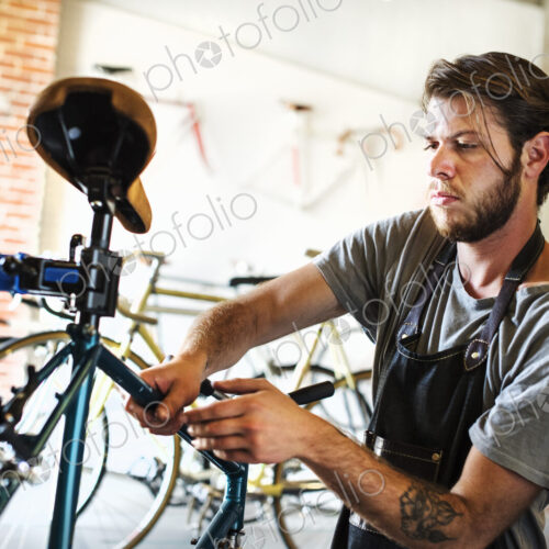 A man working in a bicycle repair shop, checking the frame of the bike. A man working in a bicycle repair shop, checking the frame of the bike.