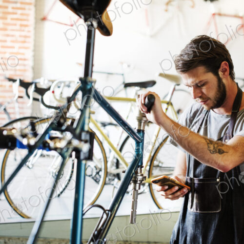 A man working in a bicycle repair shop pausing to check his messages. A man working in a bicycle repair shop pausing to check his messages.