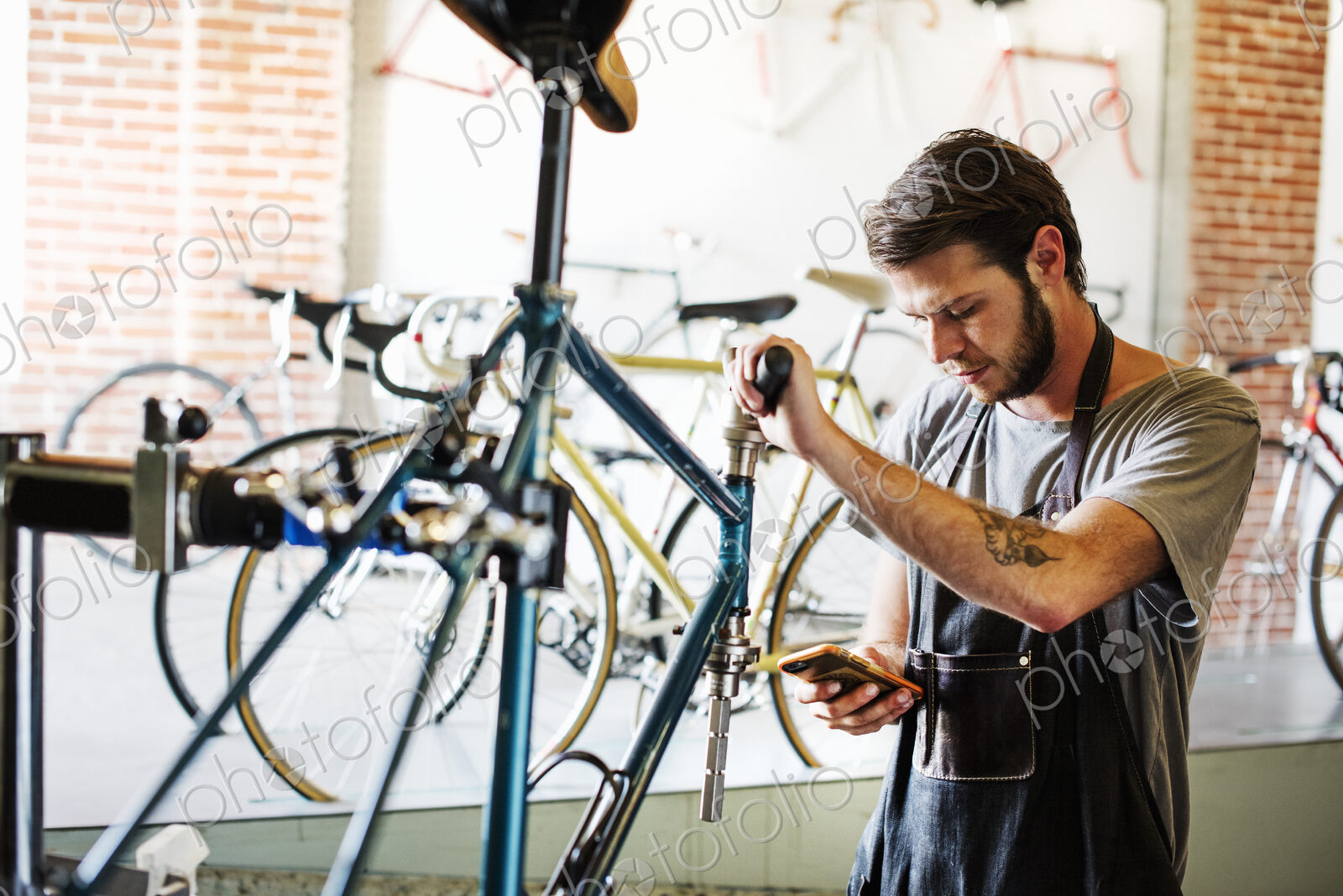 A man working in a bicycle repair shop pausing to check his messages.