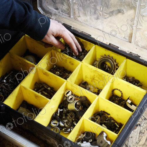 A man working in a cycle shop, reaching for parts in a box of spares.