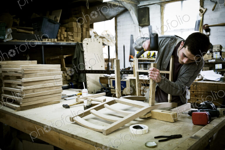 A man working in a furniture maker's workshop assembling a chair.